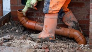Professional landscaper inspecting a blocked drain pipe in a garden