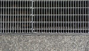 Stainless steel channel drain in outdoor kitchen flooring near appliances