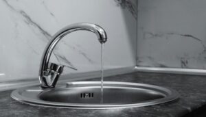 Running tap water in stainless steel sink highlighting risk of hidden drain leaks